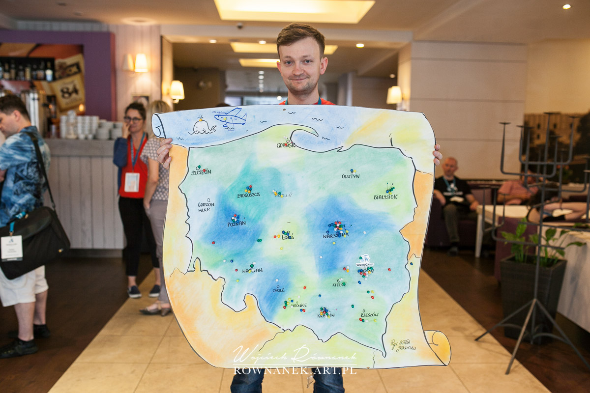 Obrazek przedstawia Szymona Skulimowskiego trzymającego mapę objaśniającą miejsce przybycia uczestników